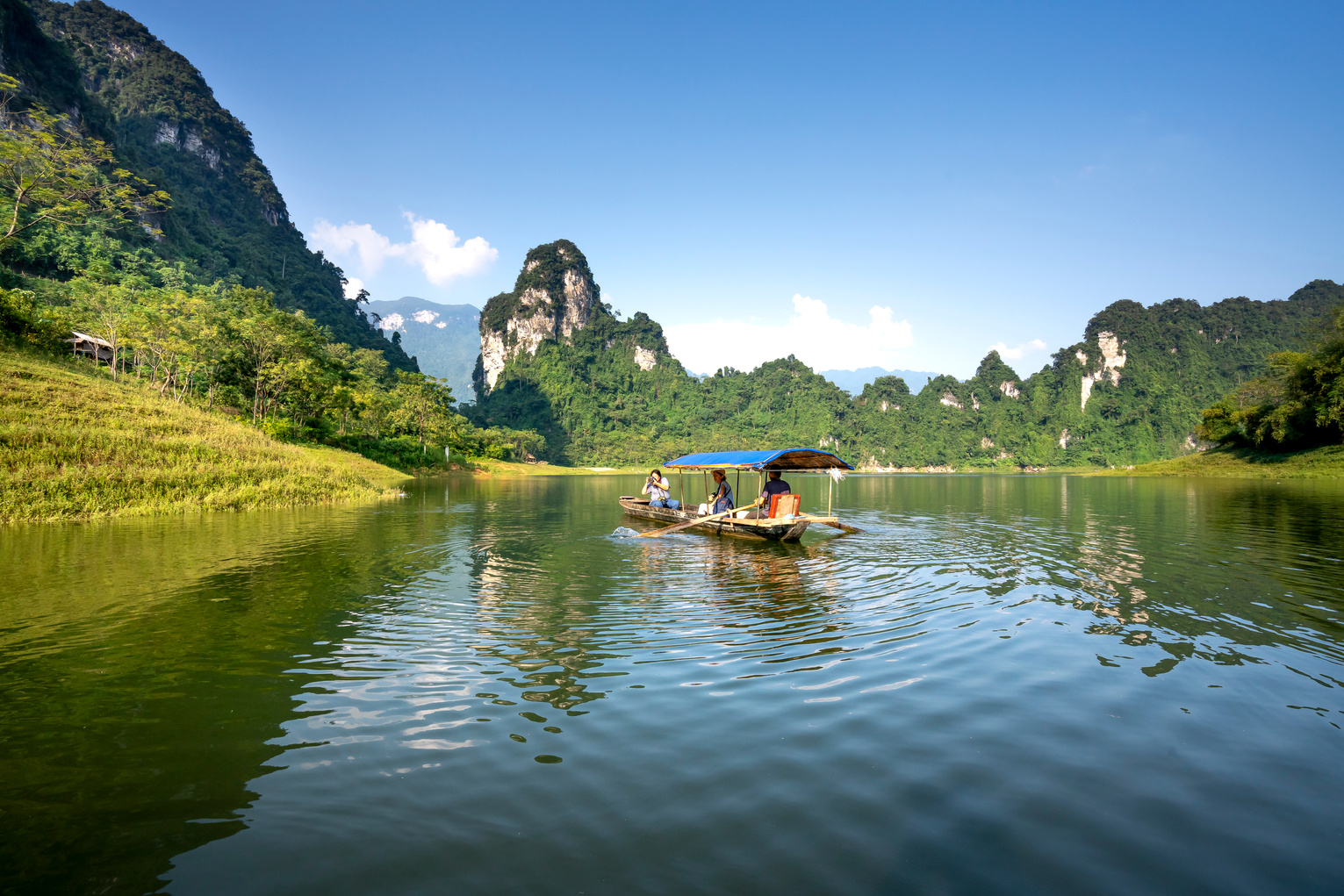 Anonymous travelers in boat sailing on river against green mountains